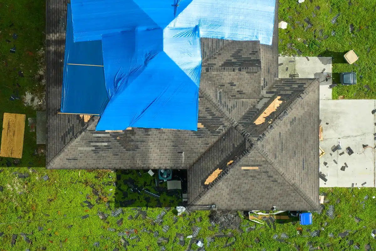 house roof with tarp and missing shingles