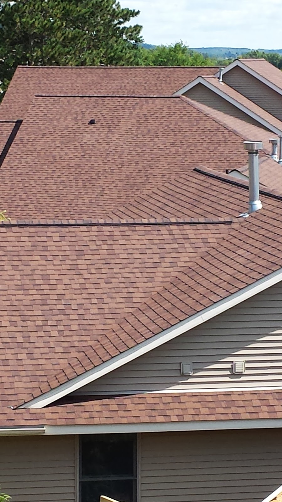 Red-brown shingle roof with ridge caps and plumbing vent flashing