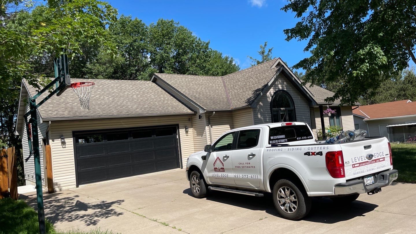 Completed shingle roof on a stone-front home with an arched entry and attached garage